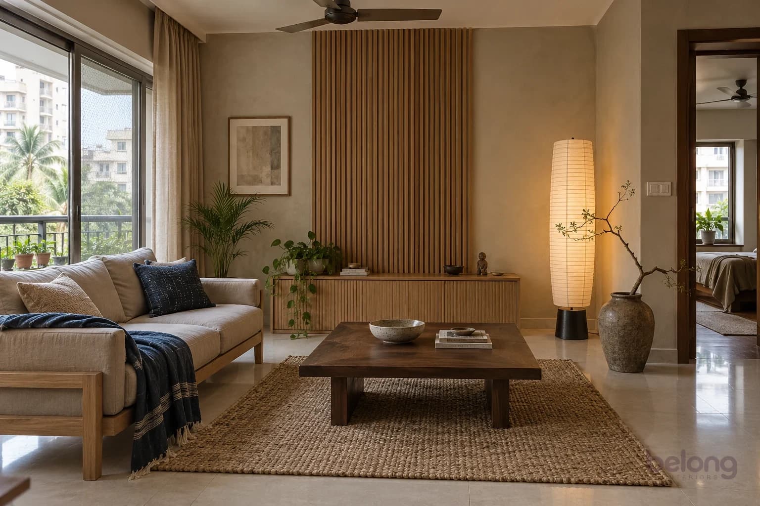 Japandi living room with a low oak sofa on the left, a walnut table and jute rug in the centre, a paper lantern on the right and a slatted wall behind.